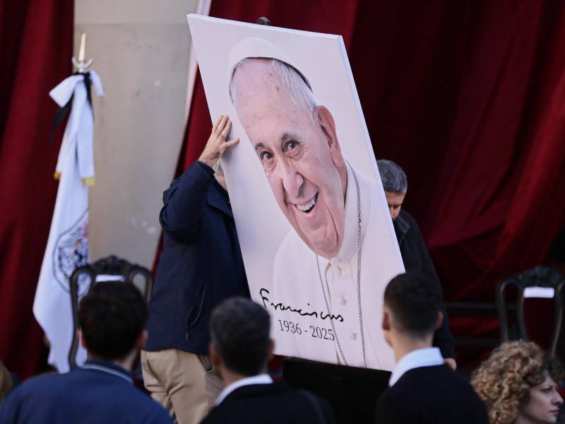Dos personas colocan una imagen del papa Francisco este sábado, durante una misa en su honor frente a la Catedral Metropolitana de Buenos Aires (Argentina).