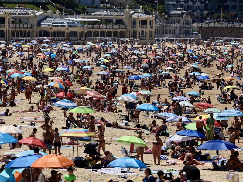 Numerosas personas en la playa de La Concha, en San Sebastián, este domingo, jornada en la que buena parte de España se encuentra en alerta amarilla por las altas temperaturas.