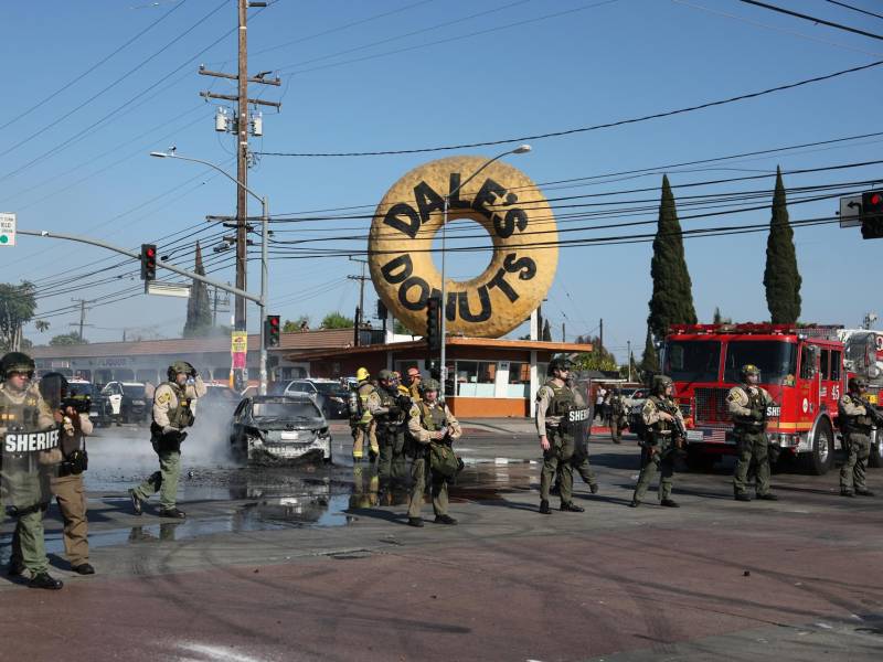 Agentes del orden fueron captados frente a un automóvil quemado, después de que ICE realizara una redada en contra de presuntos migrantes indocumentados, en Paramount.