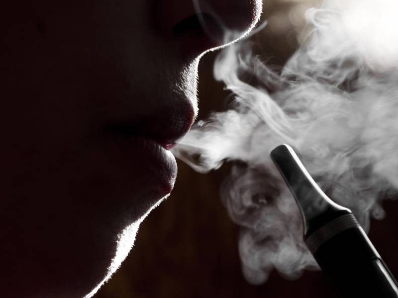 Silueta de una persona vapeando un cigarrillo eléctrico.