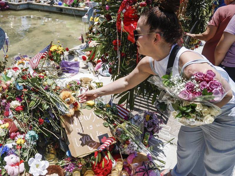 Fotografía de archivo, tomada el pasado 29 de mayo, en la que se registró a una mujer al hacer una ofrenda floral frente a la institución académica Robb Elementary School, en Uvalde.