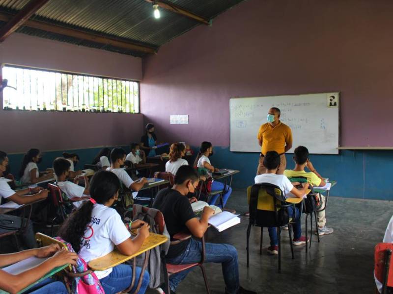Un docente imparte una clase a sus alumnos en una escuela pública.