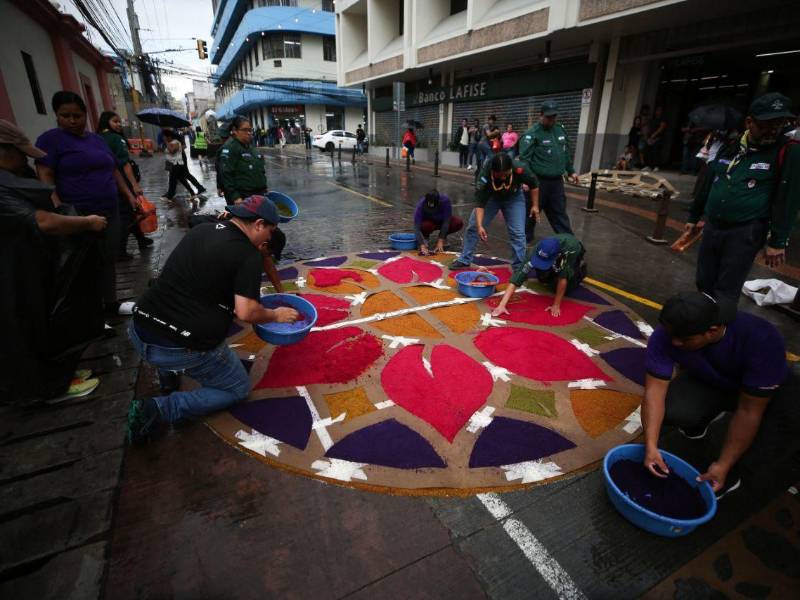 Hombres trabajan con dedicación en la confección de las tradicionales alfombras de aserrín sobre la avenida Cervantes, preparadas para el Santo Entierro de este Viernes Santo.
