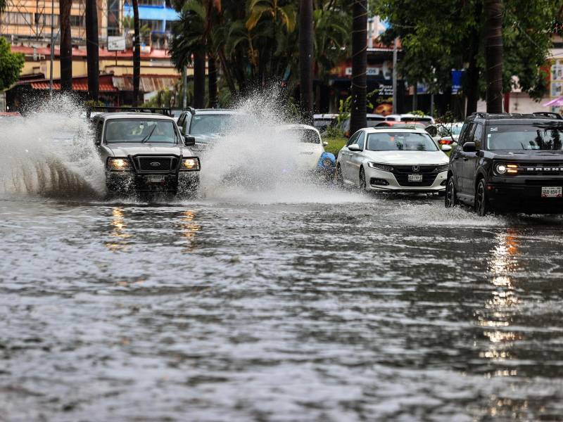 Vehículos transitan por una calle inundada debido a las fuertes lluvias hoy, en el balneario de Acapulco.