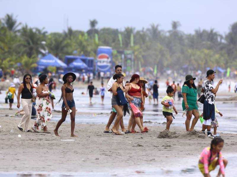 Veraneantes de diferentes partes de Honduras caminan por las playas de Tela bajo un cielo nublado a causa de la masa de aire frío que afecta principalmente Atlántida y Colón.