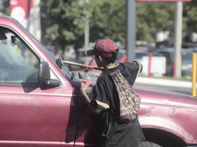 Un niño limpia carros en centro de San Pedro Sula.
