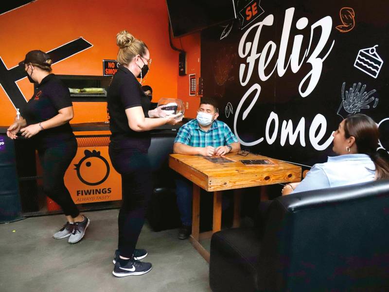 Personal de servicio al cliente de un restaurante toma la orden de dos clientes. Foto F. Martínez