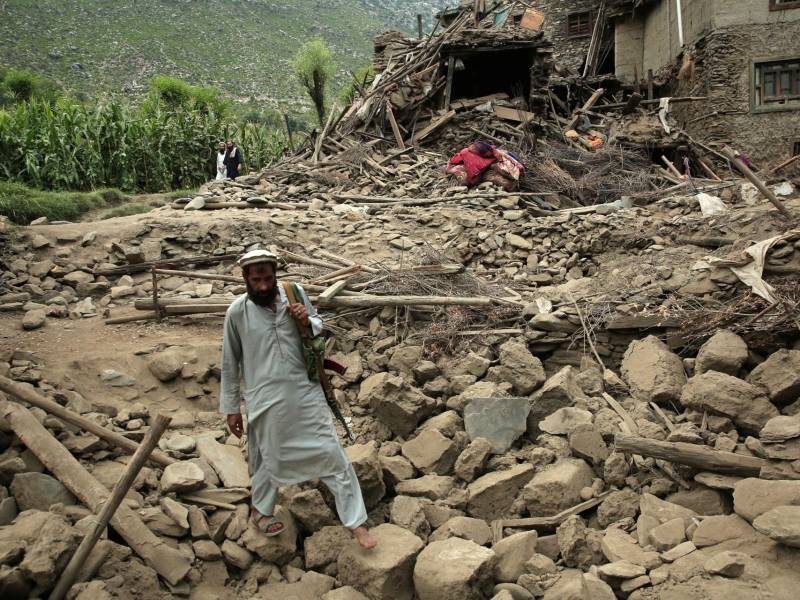 Un hombre camina sobre los escombros junto a una casa dañada después de un terremoto en Kunar, Afganistán.