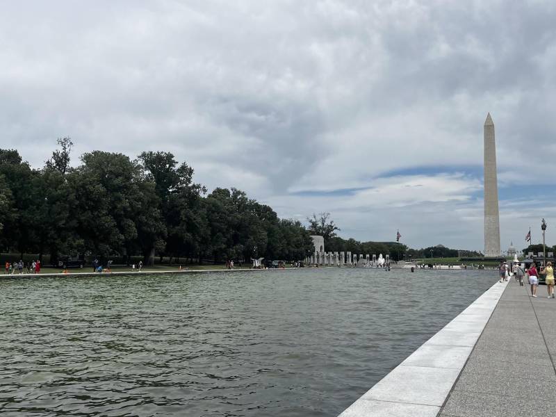 Personas caminan al lado del estanque situado frente al Monumento a Abraham Lincoln, que se llenó de algas y tiñeron de verde el agua, en Washington (EE.UU.).