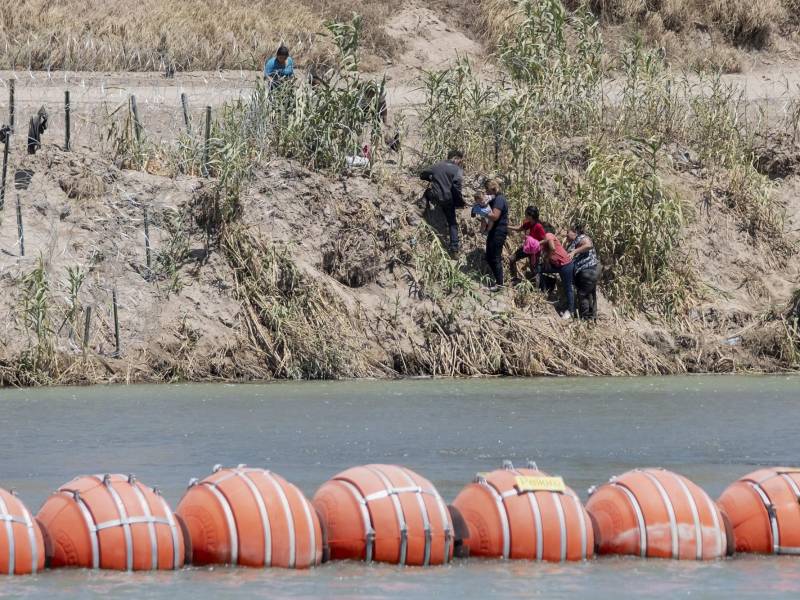 Un grupo de migrantes cruza el río Bravo en la zona donde fueron instaladas una barrera de boyas.