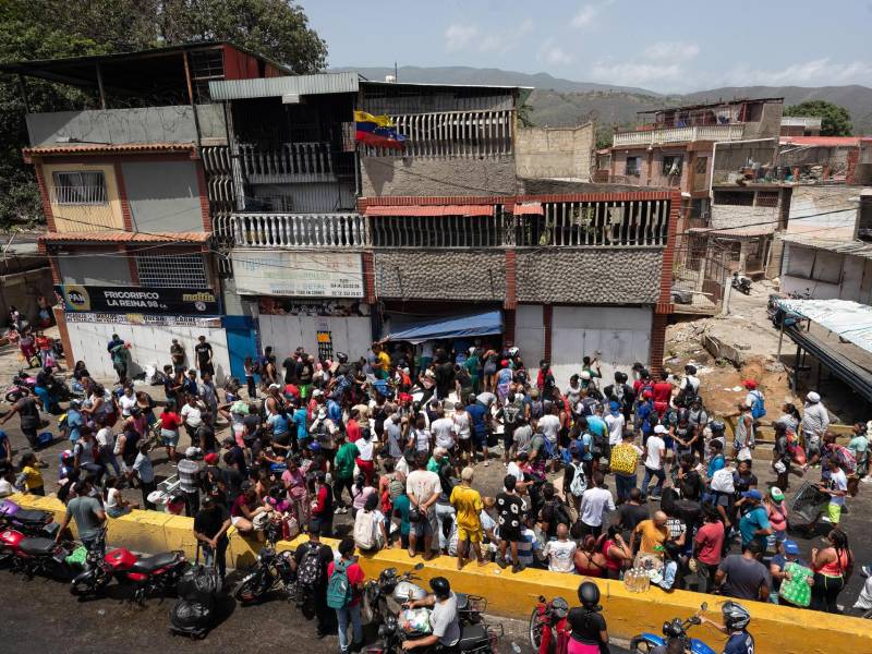 Personas observan el saqueo a un establecimiento comercial este viernes, en Catia La Mar (Venezuela). EFE/ Ronald Peña R.