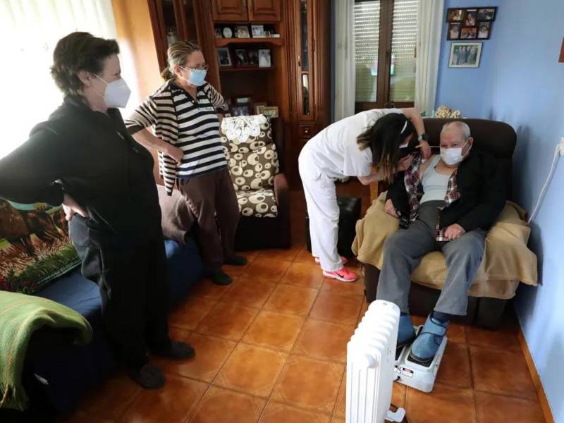 Dos enfermeras latinas atienden a una persona de la tercera edad en España.