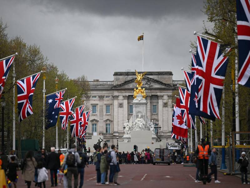 La gente camina bajo las banderas de la Unión y la Commonwealth en The Mall, mirando hacia el Palacio de Buckingham, en el centro de Londres, el 28 de abril de 2023 antes de la ceremonia de coronación de Carlos III y su esposa, Camila, como rey y reina del Reino Unido y Naciones del Reino de la Commonwealth, el 6 de mayo de 2023.