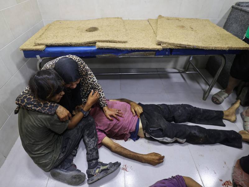 Dos personas lloran a un familiar fallecido cerca de un punto de distribución de ayuda en junio.