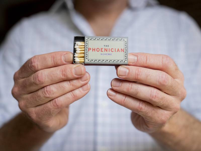 Michael Maggart con una caja de cerillos de recuerdo del estreno de “El Esquema Fenicio” de Wes Anderson.