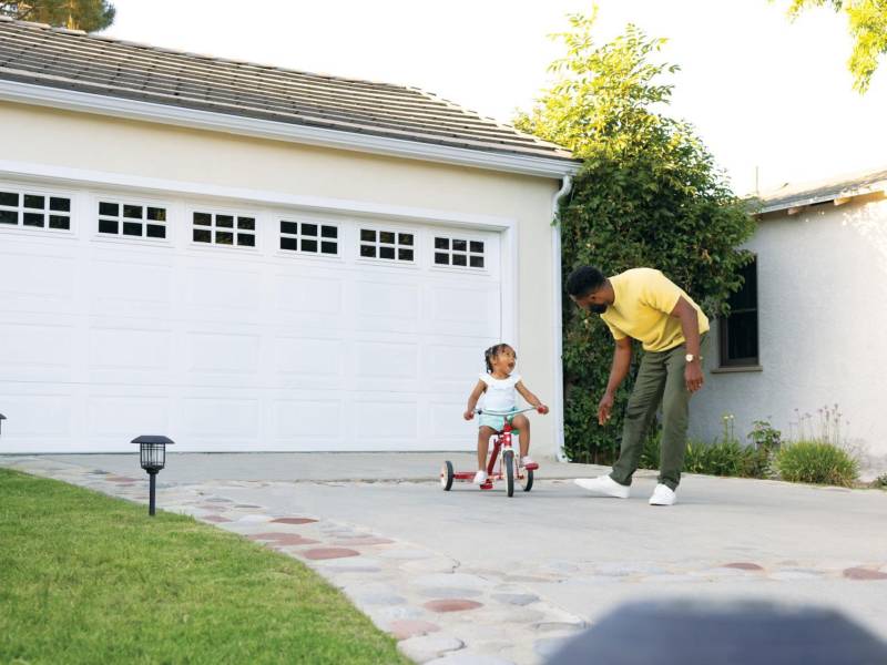 Un hombre junto a una niña en la zona exterior de una vivienda.
