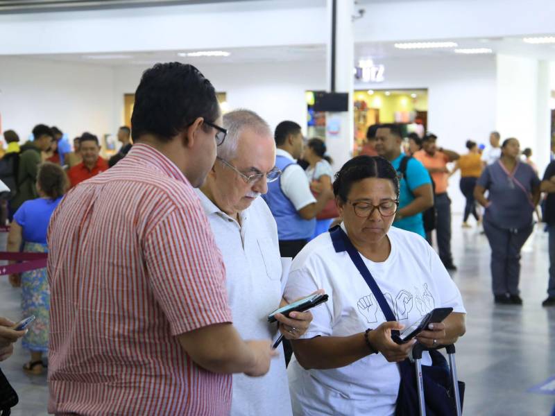 Un agente de servicio al cliente de Aduanas ayuda a estos viajeros a llenar la declaración en línea.