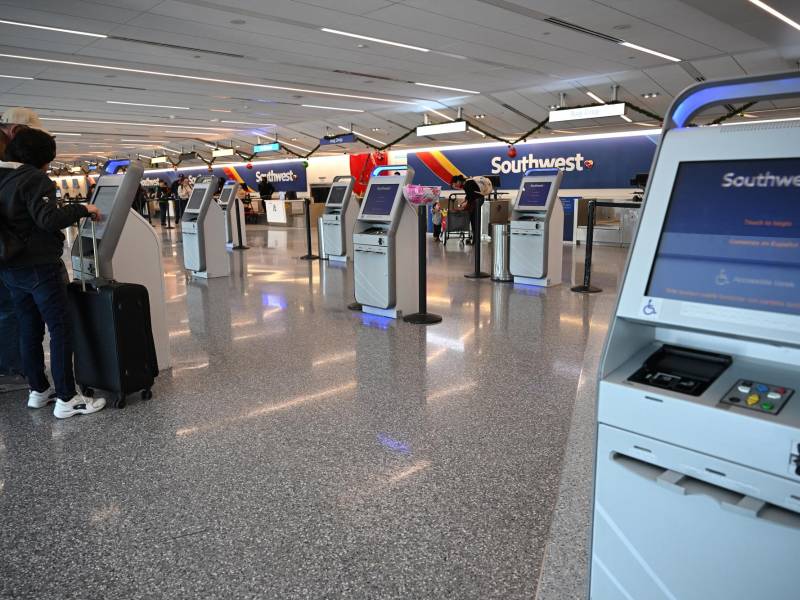 Passengers check in at an automated kiosk at a mostly empty Southwest Airlines counter area, December 28, 2022 at Los Angeles International Airport in Los Angeles. - The perfect storm of fierce snow squalls, howling wind and sub-zero temperatures forced the cancellation of thousands of flights in recent days, including around 5,900 on Tuesday and Wednesday, according to tracking site FlightAware.com. Most of the cancellations on December 27-28 were at Southwest Airlines, which pulled more than 60 percent of its flights due to cascading logistics issues. (Photo by Robyn BECK / AFP)