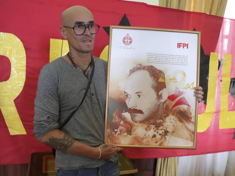 José María Reyes González hijo del guerrillero hondureño José María Reyes Mata sostiene el retrato de su padre hoy, en un foro en Tegucigalpa (Honduras).