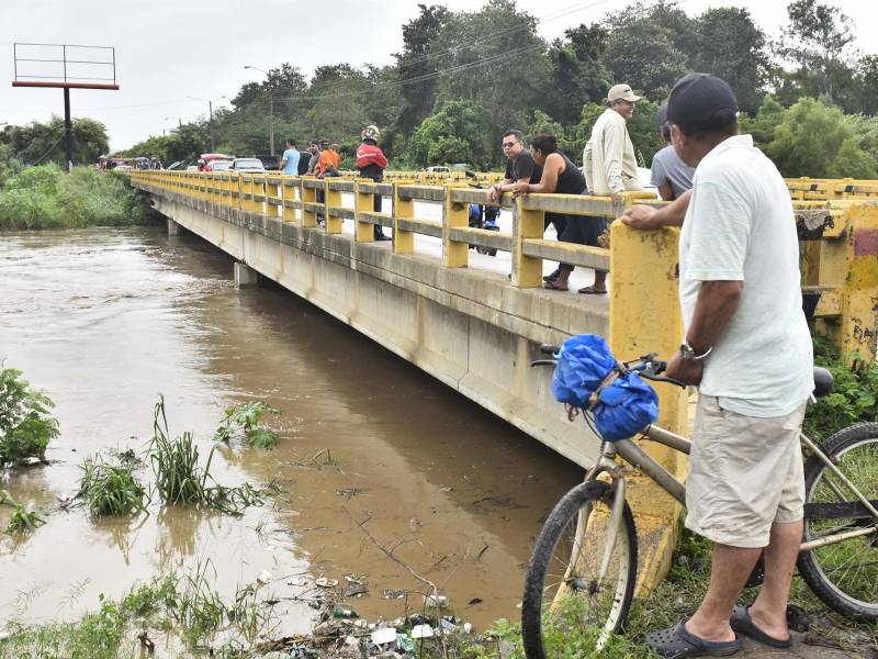 Pobladores observan el aumento del caudal del rio Chamelecón luego de que el gobierna emitiera alerta roja y ordenara evacuar las zonas bajas de la costa norte de Honduras debido al aumento de las lluvias por causa del huracán Julia, hoy en La Lima (Honduras). EFE/José Valle
