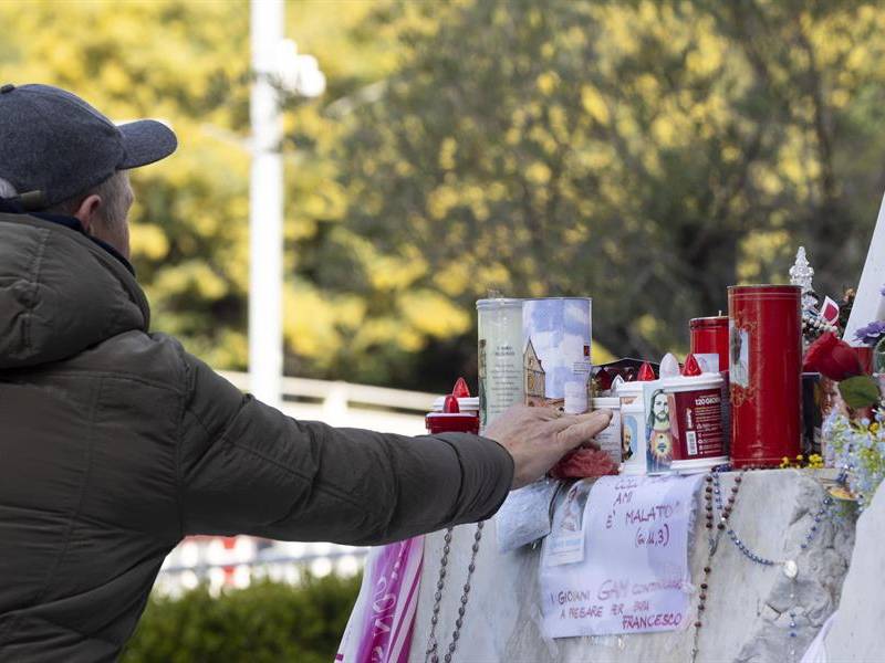 Fieles rezan frente a la estatua de Juan Pablo II en la entrada del Hospital Gemelli, donde está hospitalizado el Papa Francisco.