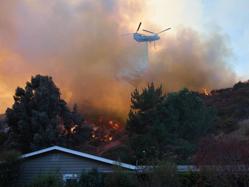 Un helicóptero arroja agua sobre una casa durante el incendio forestal de Palisades en Los Ángeles, California (EEUU).