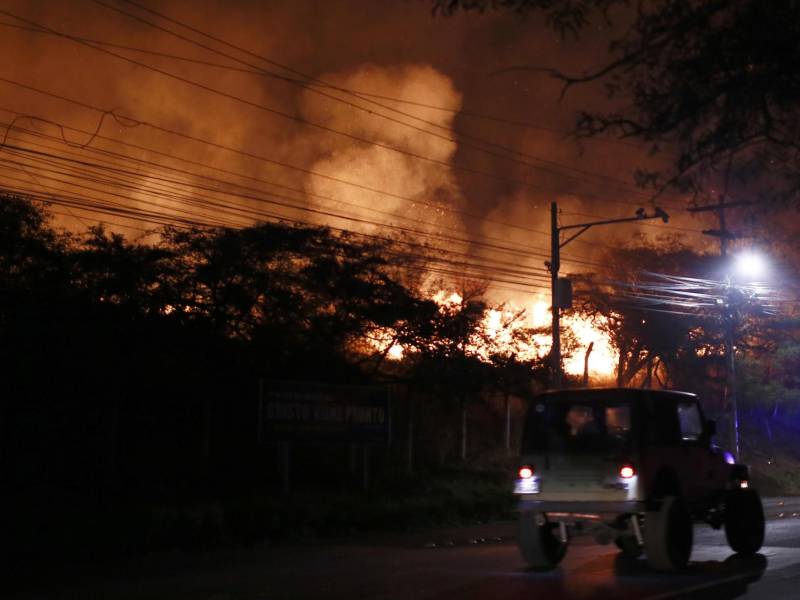 Un vehículo transita una calle frente a un incendio forestal este jueves, en un cerro cercano a Tegucigalpa (Honduras).