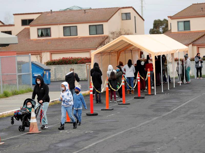 Padres con sus hijos esperan en la fila para hacerse la prueba de COVID-19 en la Escuela Primaria Ohlone en Hercules, California, EEUU.