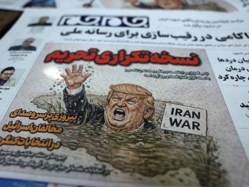 Copias del diario iraní 'Jame-Jam' con una caricatura del presidente de EE.UU., Donald Trump, y un titular en persa que dice 'Versión Duplicada de Sanciones' informando sobre la nueva amenaza económica contra Irán, junto a un quiosco en Teherán, Irán, el 22 de agosto de 2026.
