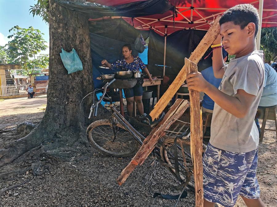 Un niño carga leña mientras su madre cocina golosinas en Puerto Lempira, el 11 de noviembre de 2021 en el departamento de Gracias a Dios (Honduras)..