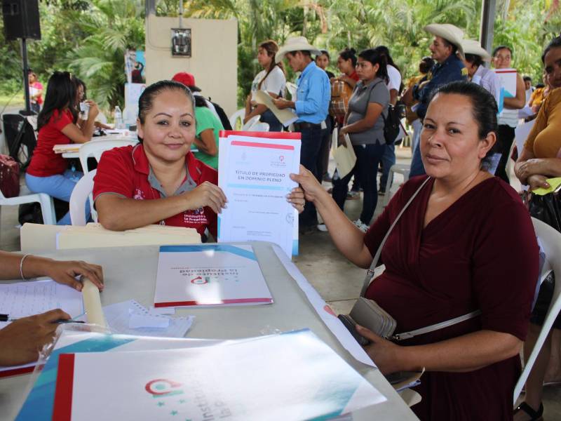 Una ciudadana recibe su título de propiedad.