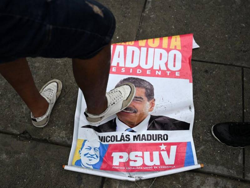 Un opositor al gobierno del presidente venezolano Nicolás Maduro pisa un cartel de campaña electoral con la imagen de Maduro durante una protesta en el barrio de Petare en Caracas el 29 de julio de 2024.