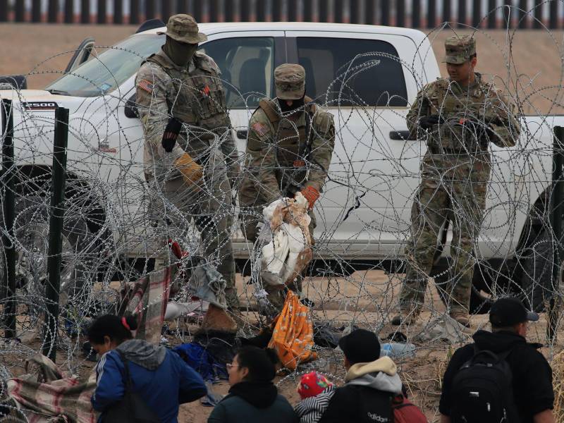 Soldados estadounidenses esperan tras una alambrada de navajas y púas mientras migrantes intentan pasar a Texas desde Ciudad Juárez (México).