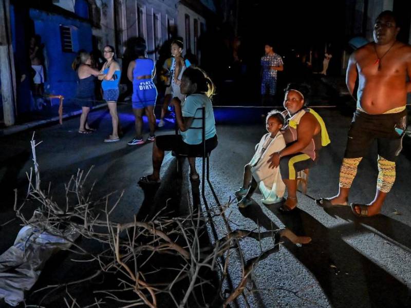 Los residentes cubanos se reúnen afuera en un vecindario bloqueado en medio de un apagón eléctrico prolongado después del huracán Ian en La Habana.