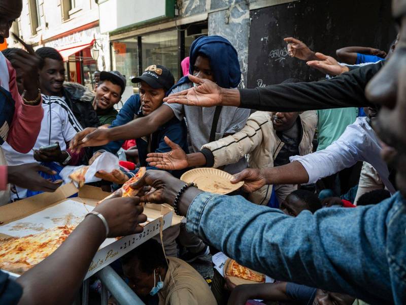 Un grupo de migrantes recibe alimentos en las afueras de un albergue en Nueva York.
