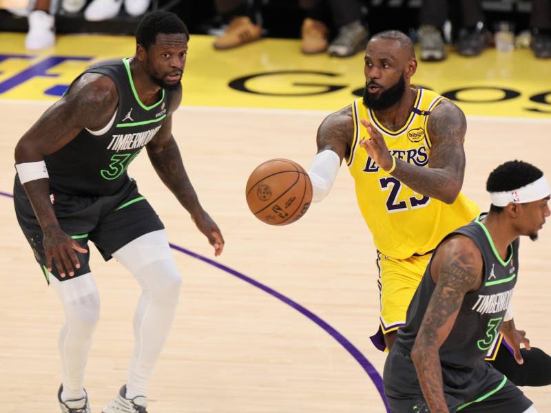 LeBron James pasa el balón entre dos rivales de Timberwolves. durante el segundo tiempo en los playoffs de la NBA en el primer juego.