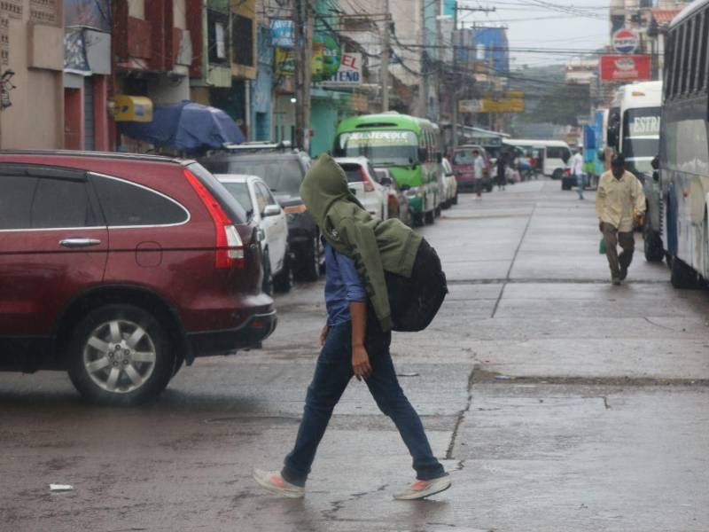 Un hondureño se protege de la lluvia en una calle de Tegucigalpa.