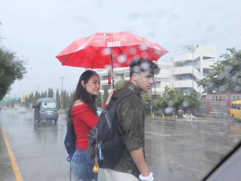 Dos jóvenes caminan durante un día lluvioso en Tegucgalpa.