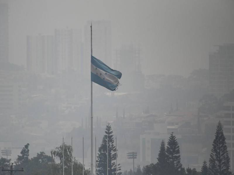 Una bandera nacional hondureña ondea en medio de una densa capa de humo que cubre Tegucigalpa en mayo de 2024.