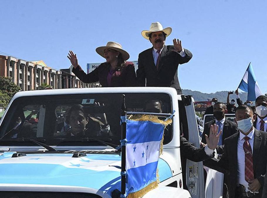 Honduran president-elect Xiomara Castro (C-L) and her husband Honduran former President (2006-2009) Manuel Zelaya, wave as they are driven along the Suyapa Boulevard towards the National Stadium, where her inauguration ceremony will take place, in Tegucigalpa, on January 27, 2022. - Honduras president-elect Xiomara Castro is due to be sworn in as the country's first woman president on Thursday, as confusion reigns over who will be head of congress during her four-year term. (Photo by Orlando SIERRA / AFP)