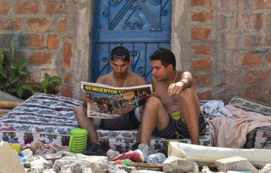Dos personas damnificadas leen un periódico local.