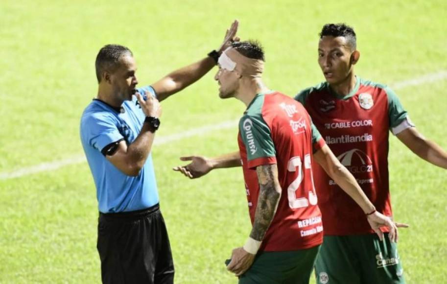 El zaguero uruguayo Mathías Techera, que también tuvo que recibir un vendaje en su cabeza, le reclama al árbitro Melvin Matamoros, junto al capitán Allan Banegas.