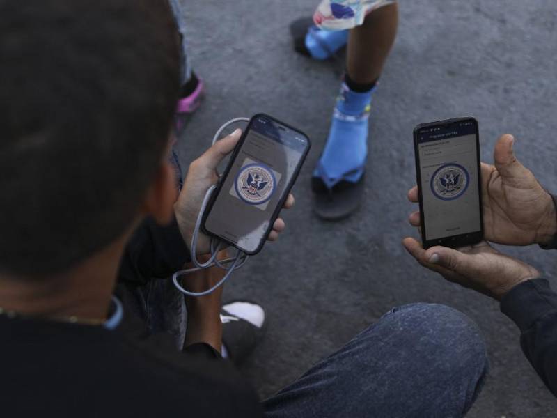 Migrantes navegan por la aplicación móvil CBP One en busca de una cita para ingresar a los Estados Unidos.