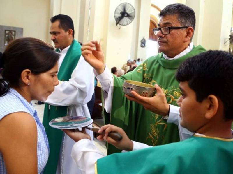 El padre José Canales entrega el cuerpo de Cristo a una feligresa. Foto: Franklin Muñoz