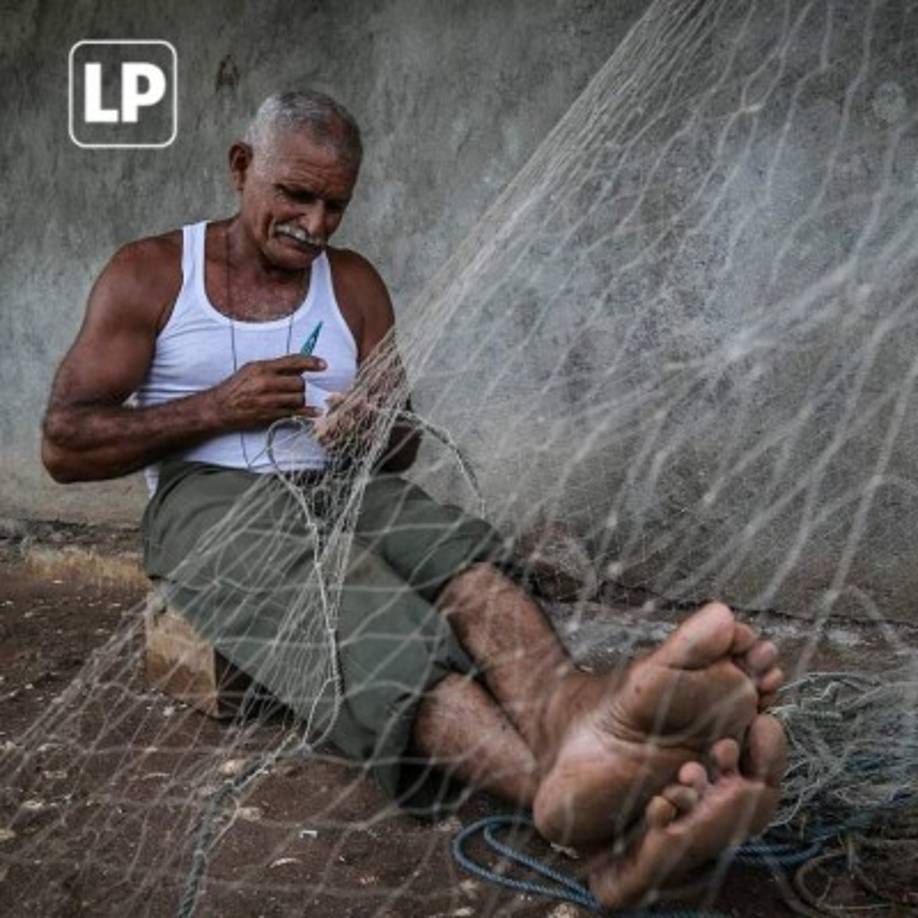 Este laborioso abuelo repara su red de pescar.