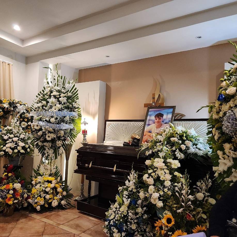 A su lado se observaba el féretro rodeado de flores blancas y amarillas.