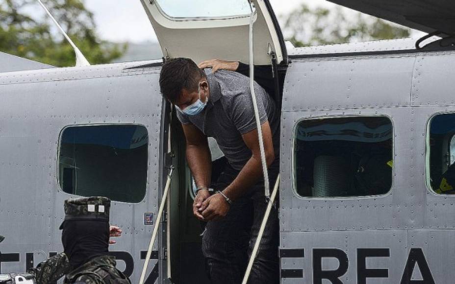 Members of the Anti-Drug Trafficking Directorate and the Military Police of Public Order guard Honduran Oscar Fernando Santos Tobar, aka 'Teto', accused of drug trafficking and wanted for extradition by the US, at the Hernan Acosta Mejia air base in Tegucigalpa, on August 23, 2021. - Santos, wanted for extradition by the US District Court for the Eastern District of Texas, is allegedly responsible for the crime of conspiracy to manufacture and distribute five kilos of cocaine. He was captured in the municipality of El Paraiso, department of Copan, a border area with Guatemala, and then transferred to the Honduran capital. (Photo by Orlando SIERRA / AFP)