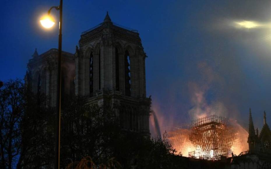 Las llamas se ven a través de los andamios de la catedral luego de varias horas por apagar el fuego.