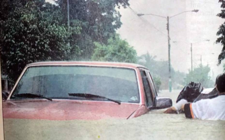 Un hombre pasa junto a un vehículo cubierto de agua.