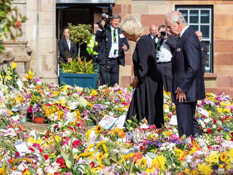 El rey Carlos III y su esposa observan las ofrendas florales para la reina Isabel II en las afueras del palacio de Buckingham.